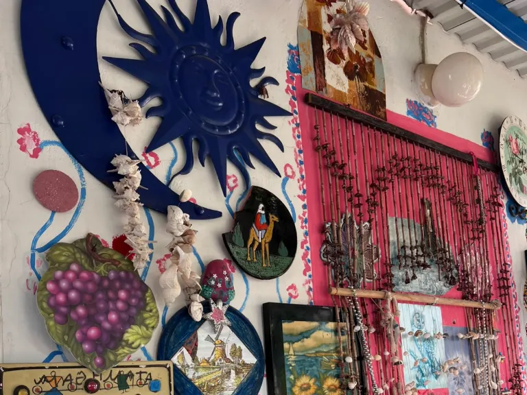 Bemalte Wand mit Sonne, Mond, Bildern und Muschelvorhang im Blue Shell House