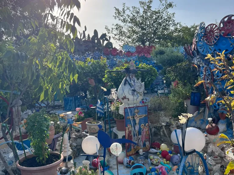 Garten mit blauen und roten Radkappen, Kugellampen und Ikone am Blue Shell House
