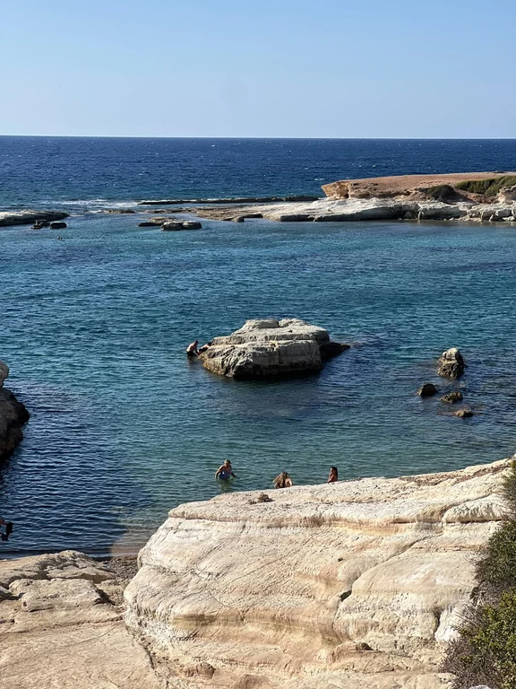 Small rocky cove with clear turquoise water below Olive Tree Beach
