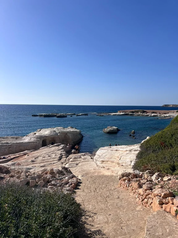 Path over pale limestone rocks down to the cove at Olive Tree Beach
