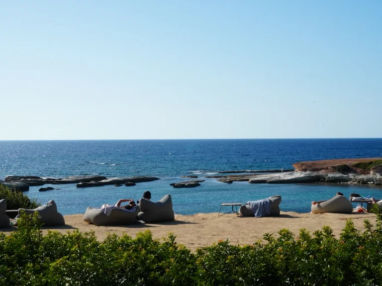 Grey bean bags on the sand with a view of the sea at Olive Tree Beach