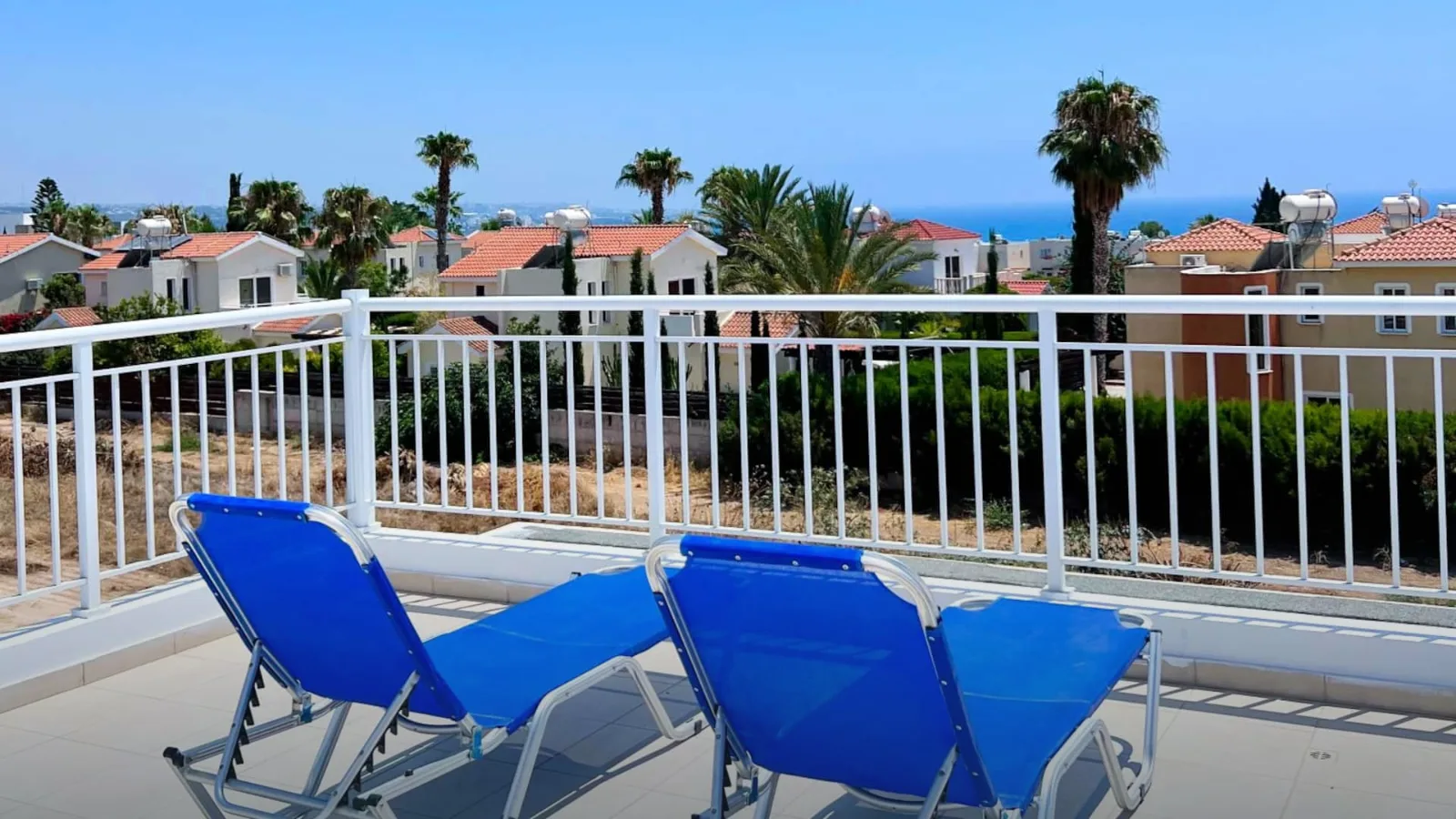 Dachterrasse der Villa Halia in Coral Bay mit Sonnenliegen, Palmen und Meerblick